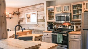Una cocina con armarios de madera, estufa, microondas y refrigerador.