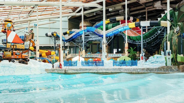 Parque acuático interior con múltiples toboganes y zona de piscina.