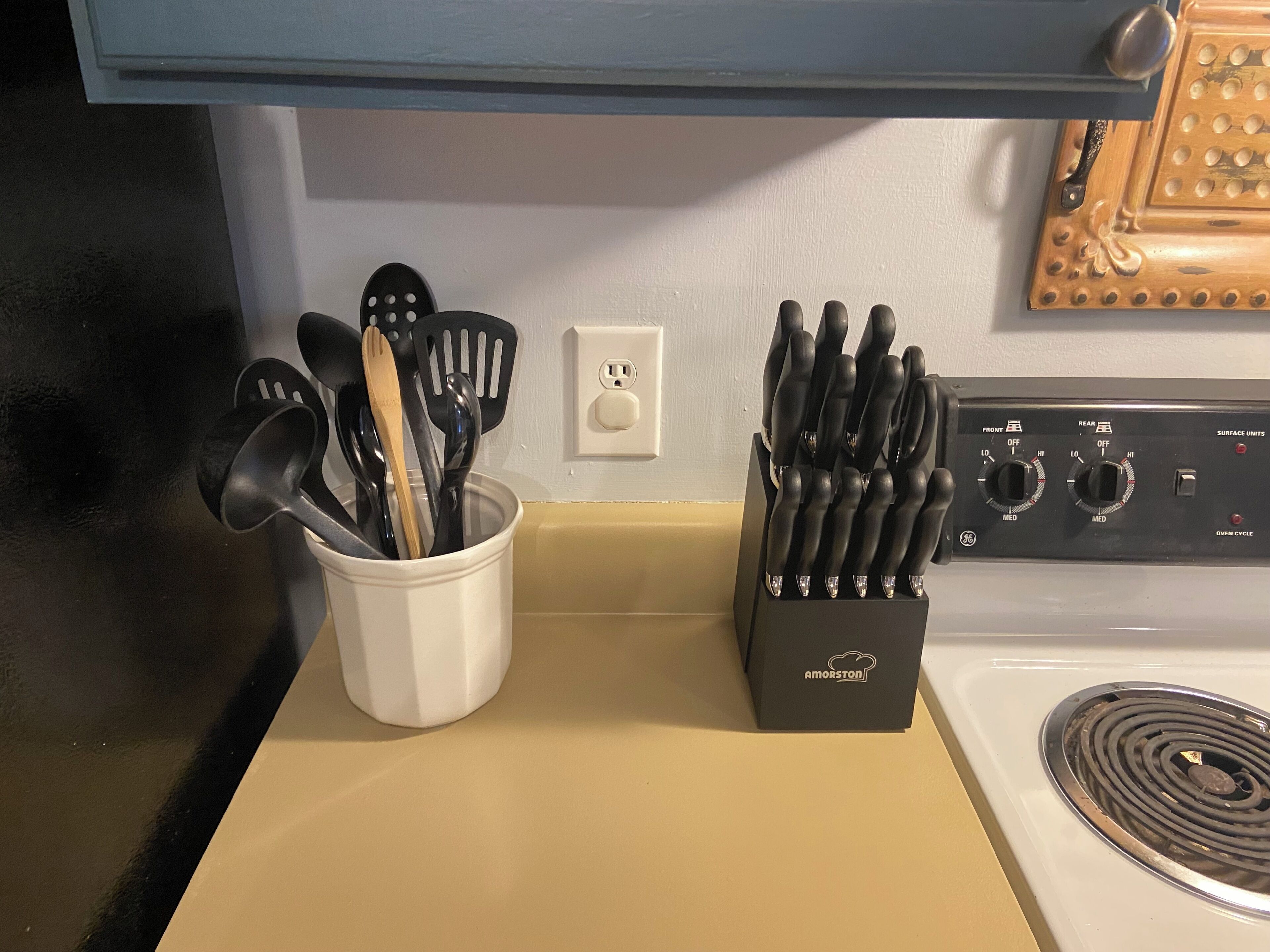 A kitchen counter with a utensil holder and a stove.