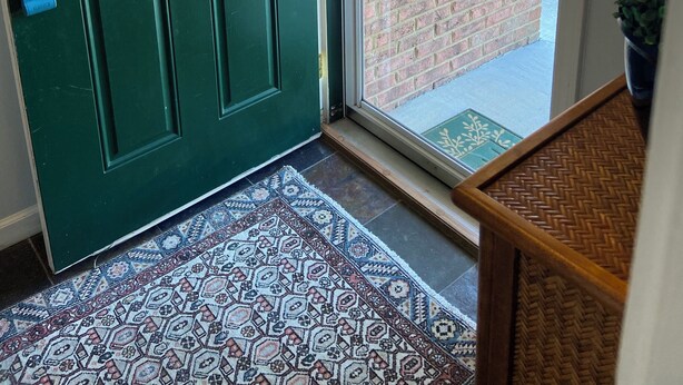 A green door with a wreath, a patterned rug, and a brick wall visible through the door. - Long term chic en suite 2 bedroom Corp Rental in N. Knox/Powell with WiFi, AC (Powell)