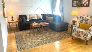 A living room with a sectional sofa, a patterned armchair, a coffee table, and a rug. - Long term chic en suite 2 bedroom Corp Rental in N. Knox/Powell with WiFi, AC (Powell)
