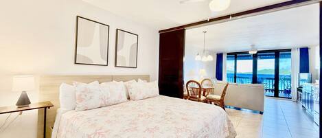 Une chambre d’hôtel avec un grand lit, un ventilateur de plafond et une vue sur le balcon.