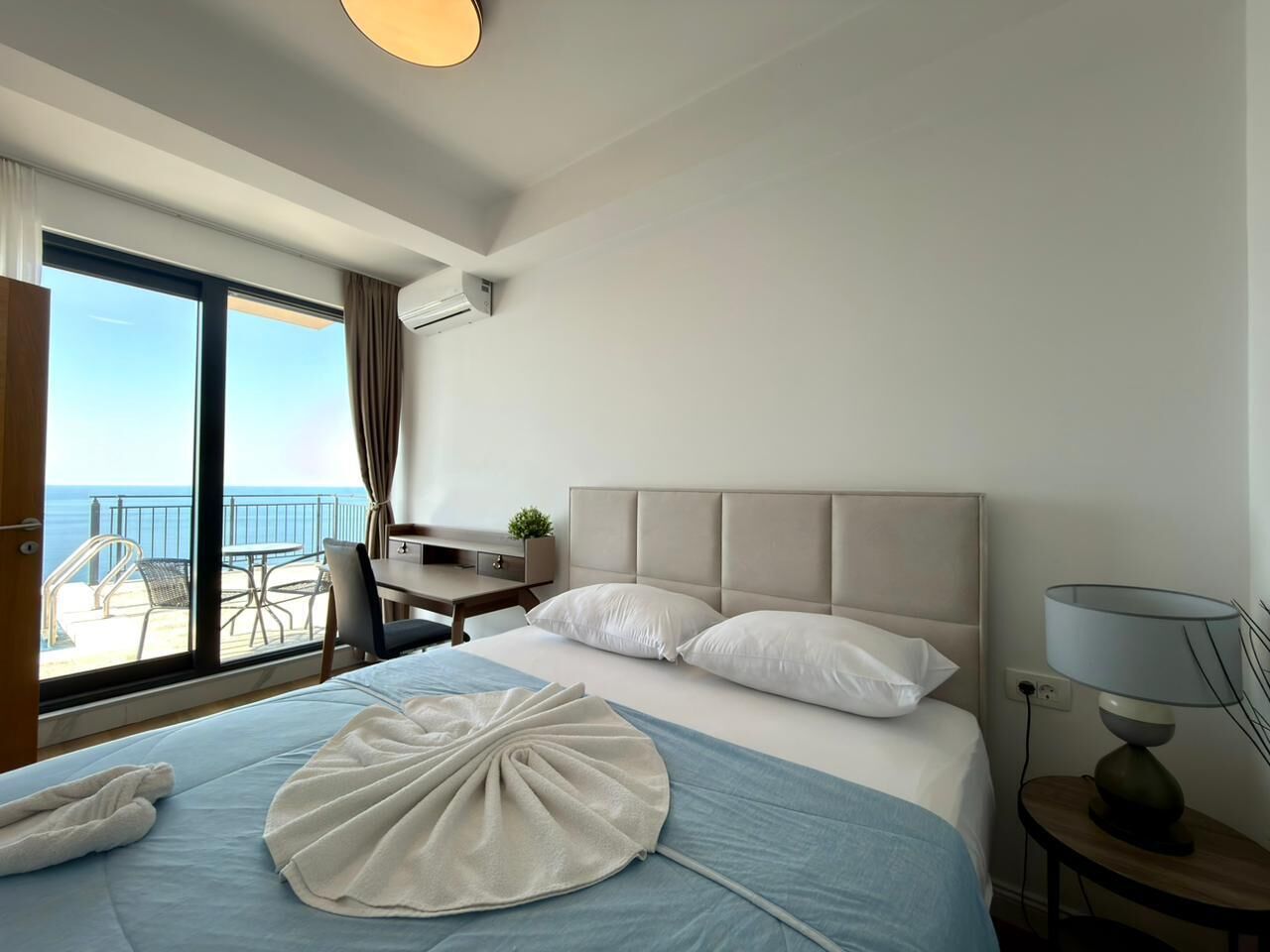 Une chambre d’hôtel avec un lit, un bureau, une chaise et une vue sur la mer.