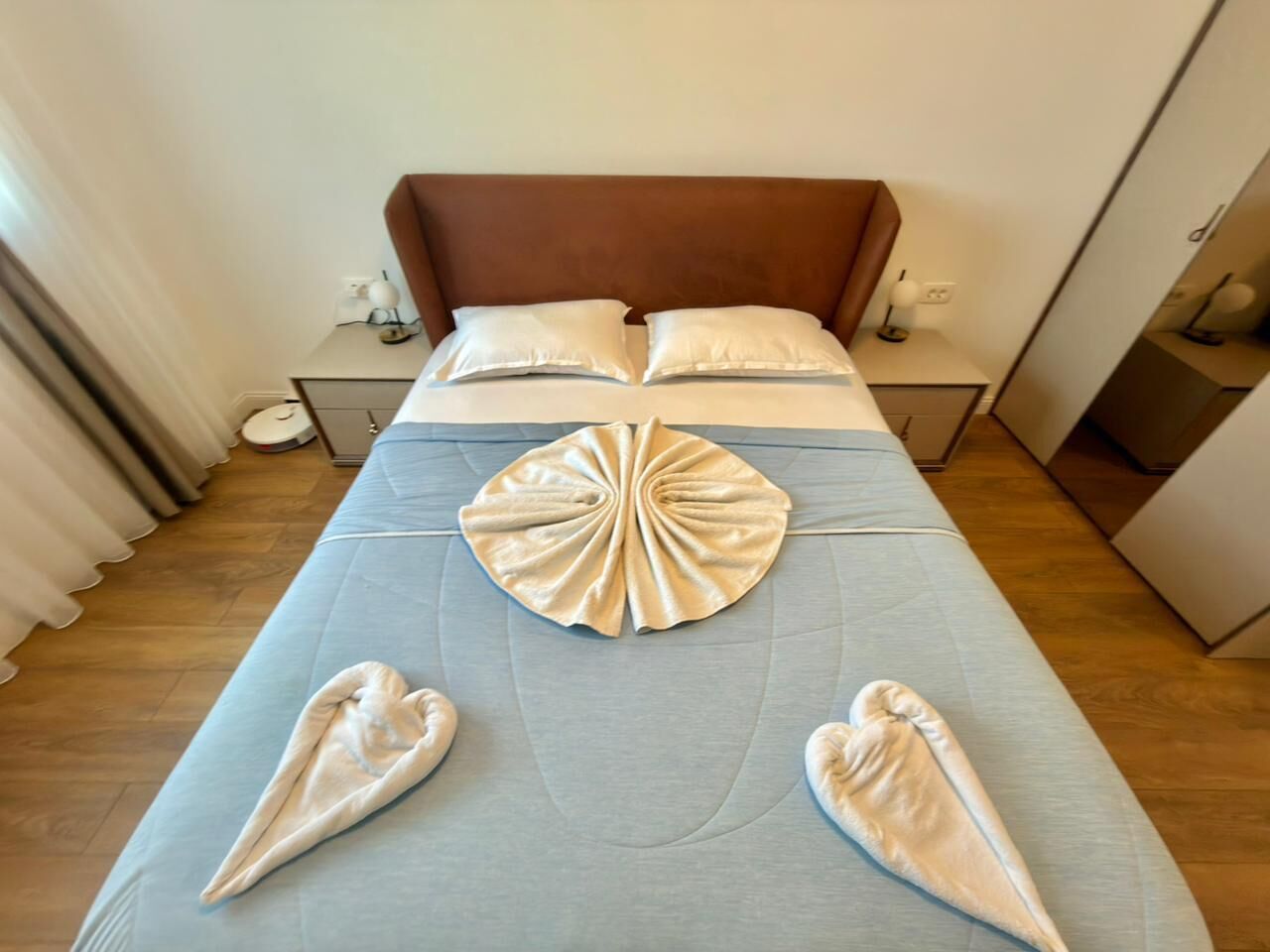 A hotel room with a bed, pillows, bedside tables, and a decorative towel arrangement.