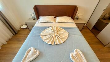 A hotel room with a bed, pillows, bedside tables, and a decorative towel arrangement.