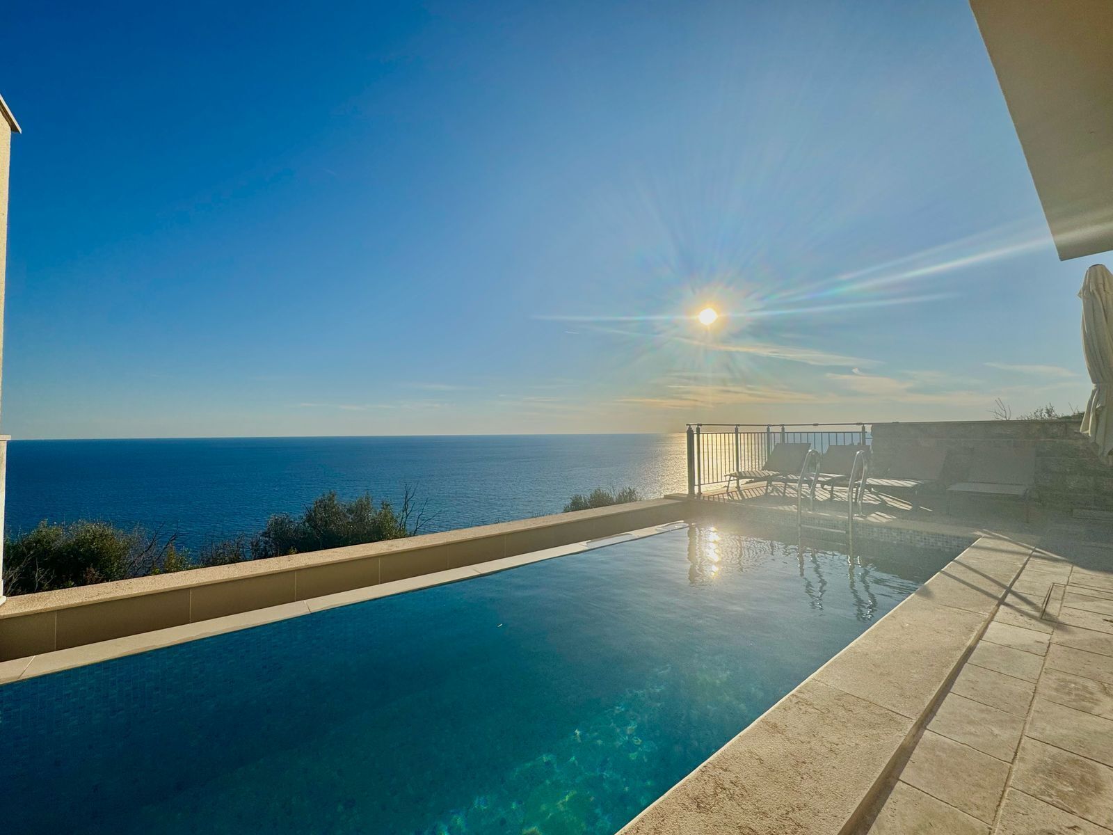 A clear blue sky, a swimming pool, and a view of the sea.
