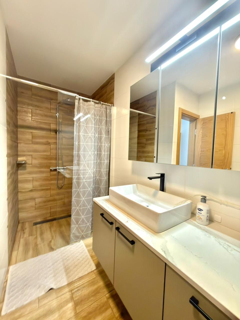 A modern bathroom with a shower, a sink, and a mirror.