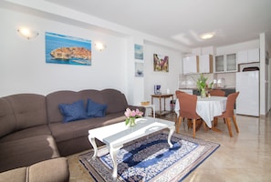 Cozy living space with a sofa, coffee table, and dining area, featuring a round table and four chairs.