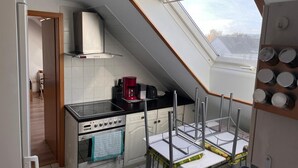 A kitchen with a skylight, a stove, and a coffee maker. - NR 4 DG 2 rooms for companies and families (Nieder Vellmar)