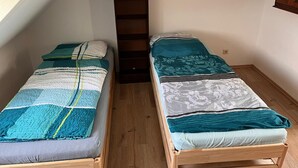 Two single beds with wooden frames in a room with sloped ceilings and wooden flooring. - NR 4 DG 2 rooms for companies and families (Nieder Vellmar)