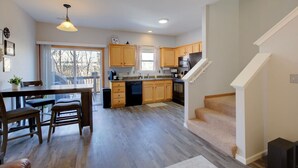 A modern kitchen with wooden cabinets, a dining area with a table and chairs, and a staircase leading to another level. - 2 Kings, Workspace, Garage 3bdrm - Pastore`s Place (Manhattan)