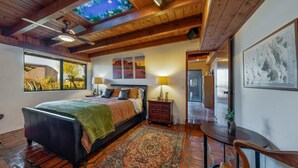 Een slaapkamer met een groot bed, een plafond dat doet denken aan een nachthemel, een houten plafond, een raam, een nachtkastje, een lamp, een stoel, een vloerkleed en een deur.