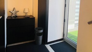 A hallway with a black carpet, a small trash bin, a star decoration, and a lamp on a black surface. - NocasHouse Porto (Campo)