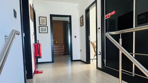A modern hotel hallway with a wooden floor, a staircase with metal railings, and a door leading to another room. - NocasHouse Porto (Campo)