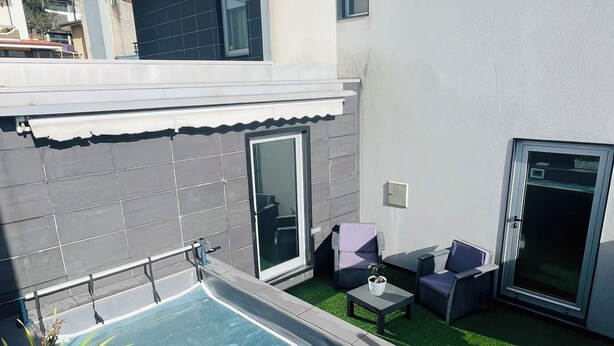 A modern outdoor pool area with a glass door, a small seating area with a table and chairs, and a potted plant. - NocasHouse Porto (Campo)