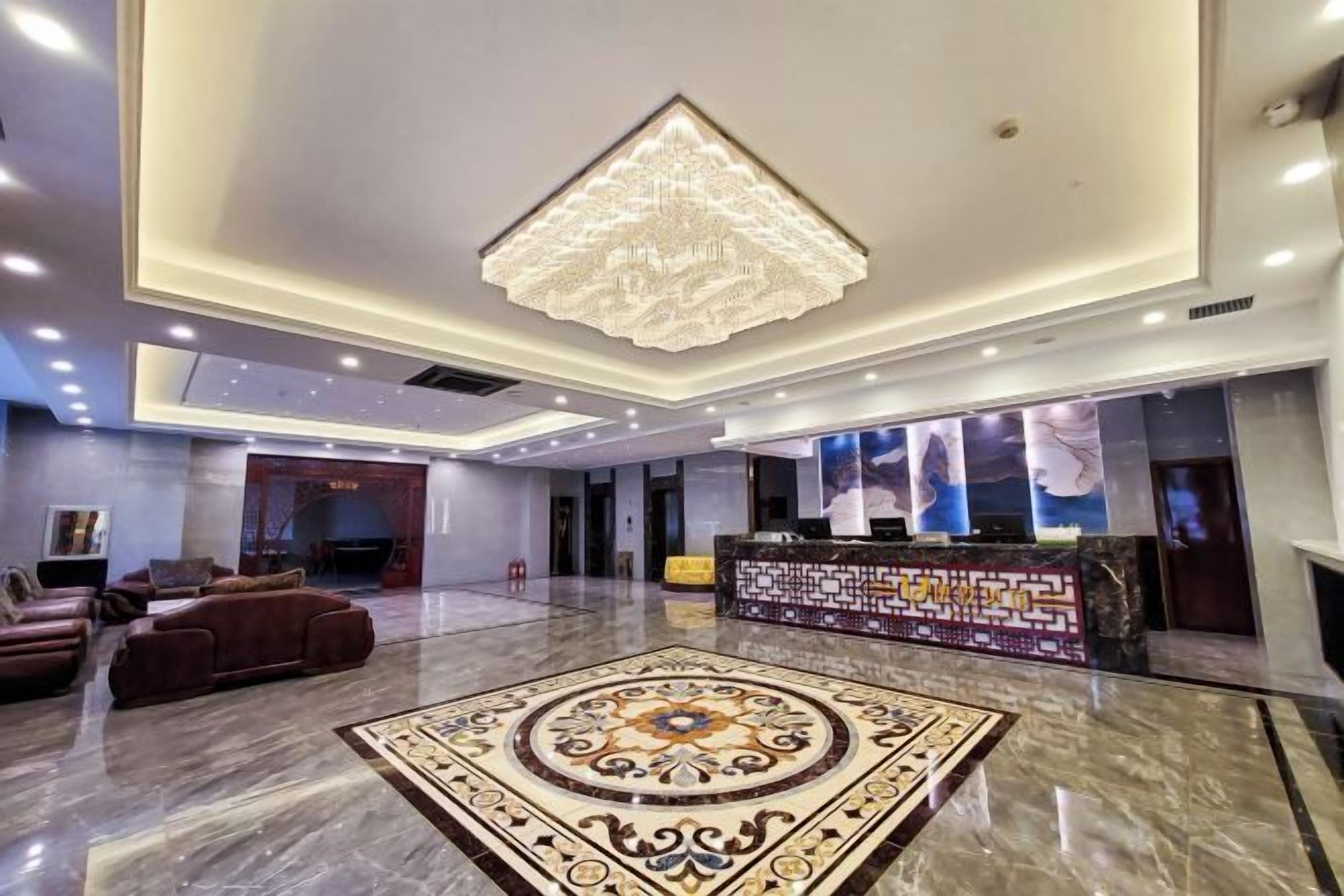 Un vestíbulo de hotel con una recepción, zona de estar y una alfombra decorativa.