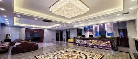 Un vestíbulo de hotel con una recepción, zona de estar y una alfombra decorativa.