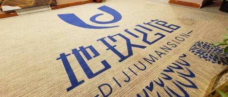 A hotel entrance with a doormat displaying the name "DIJUMANSION" in large blue letters.