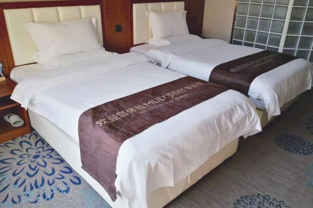 Una cama doble con sábanas blancas y una almohada decorativa marrón.