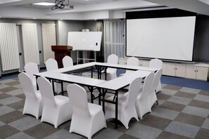 A conference room with a large table, white chairs, a whiteboard, and a projection screen. - Diyu Mansion Hotel (Harbin Central Street) (Harbin)