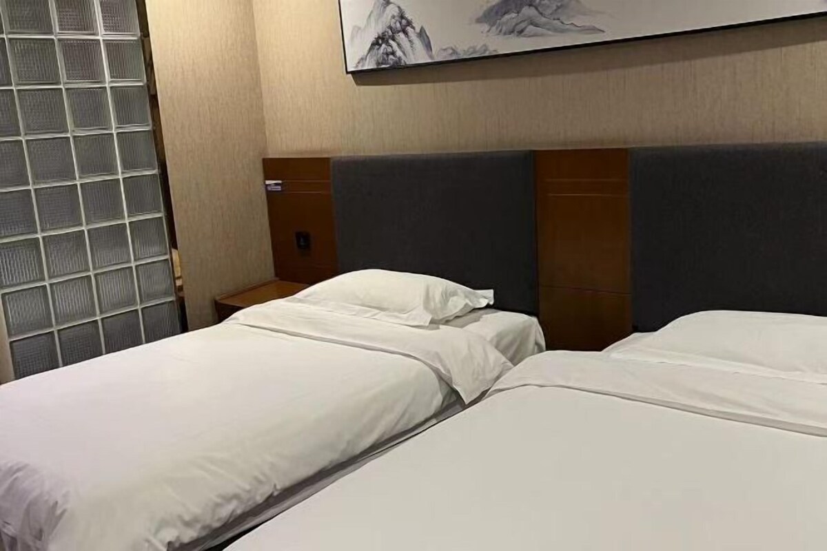 A hotel room with two beds, a nightstand, and a wall-mounted artwork.