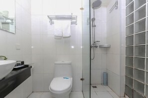 A modern bathroom with a white toilet, a glass-enclosed shower, and a sink with a mirror above it. - Diyu Mansion Hotel (Harbin Central Street) (Harbin)