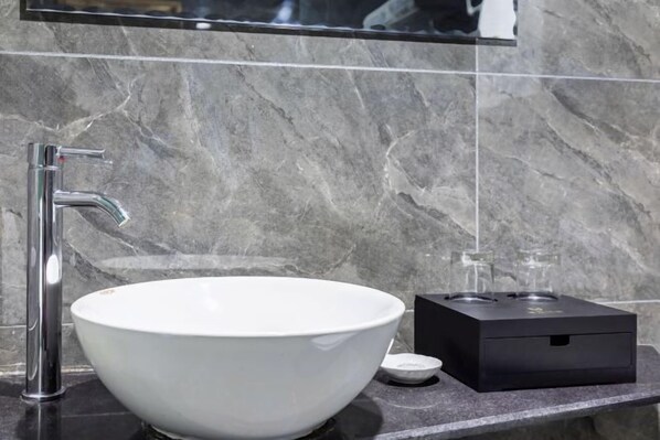 A modern bathroom with a white ceramic sink, a chrome faucet, and a black electric heater on a marble countertop. - Diyu Mansion Hotel (Harbin Central Street) (Harbin)