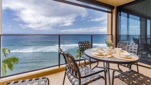 Un balcon avec une table dressée pour le dîner, donnant sur l’océan.
