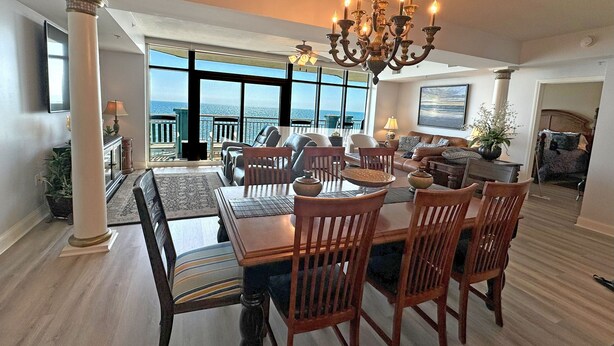 Un comedor espacioso con candelabro, ventanas amplias y vista al océano.