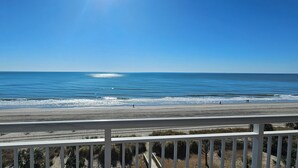 Vista de la playa desde un balcón con barandilla.