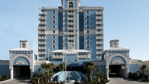Un hotel de varios pisos con un atrio central, balcones en cada planta y una fachada simétrica.