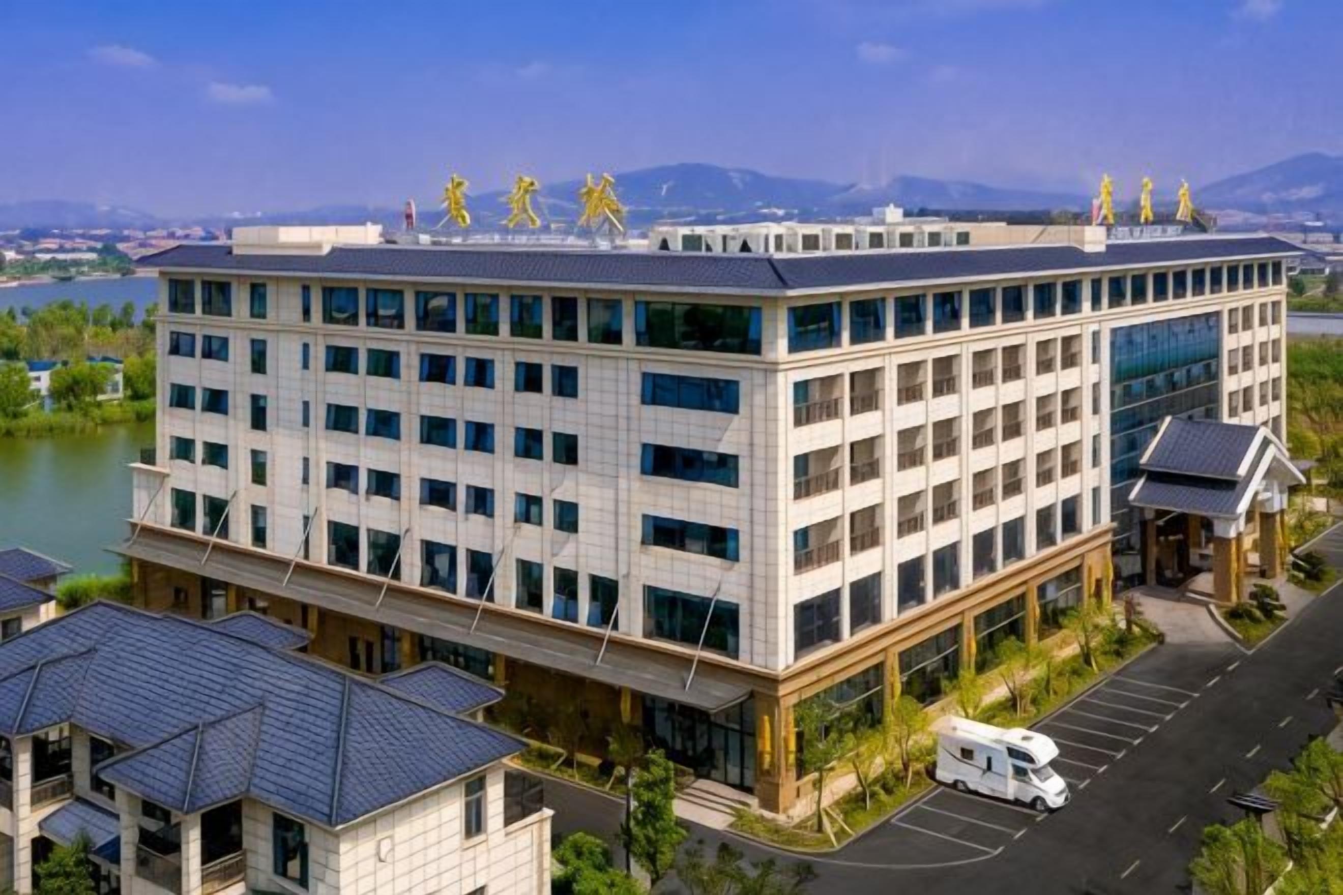 Un hotel de varios pisos con un diseño moderno, que cuenta con un área de estacionamiento y vistas a un lago.