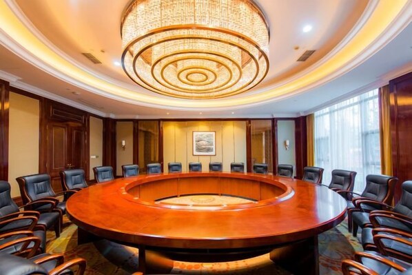 Un salón de conferencias con una mesa redonda, sillas y una araña de cristal.
