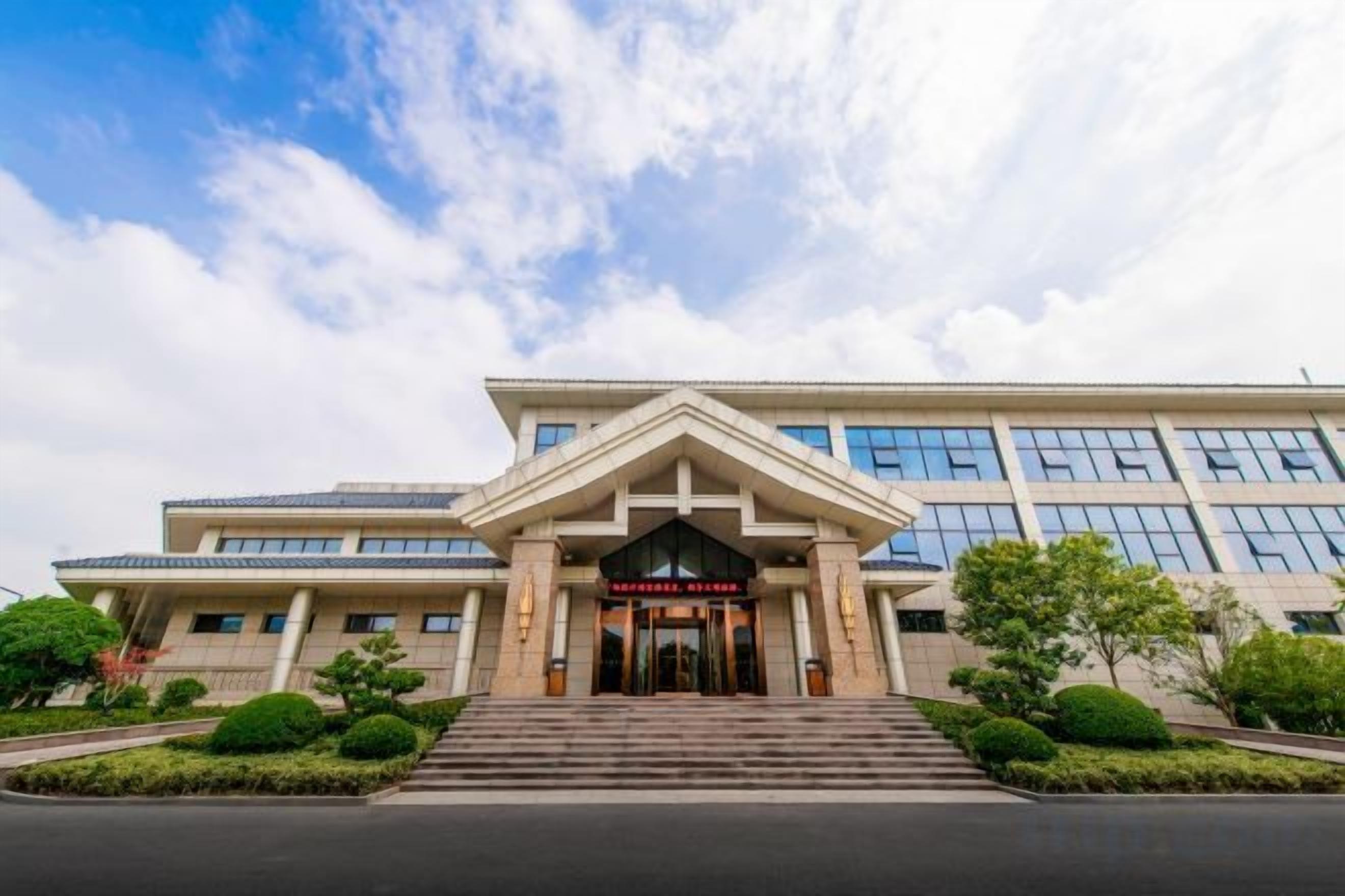 A modern building with a prominent entrance, steps leading up to it, and a clear sky above.