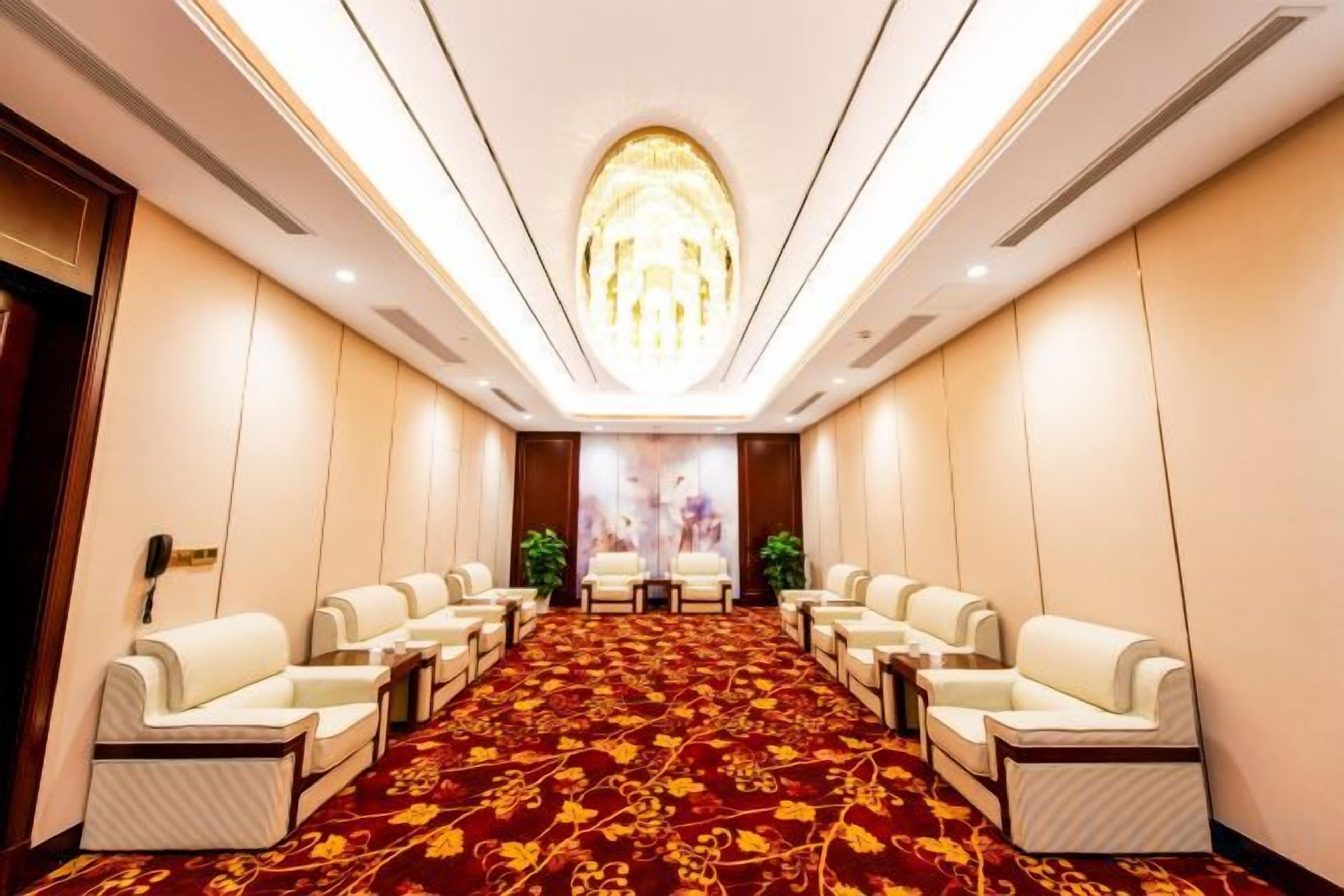 A conference room with a long table and multiple chairs, a patterned carpet, and a chandelier.
