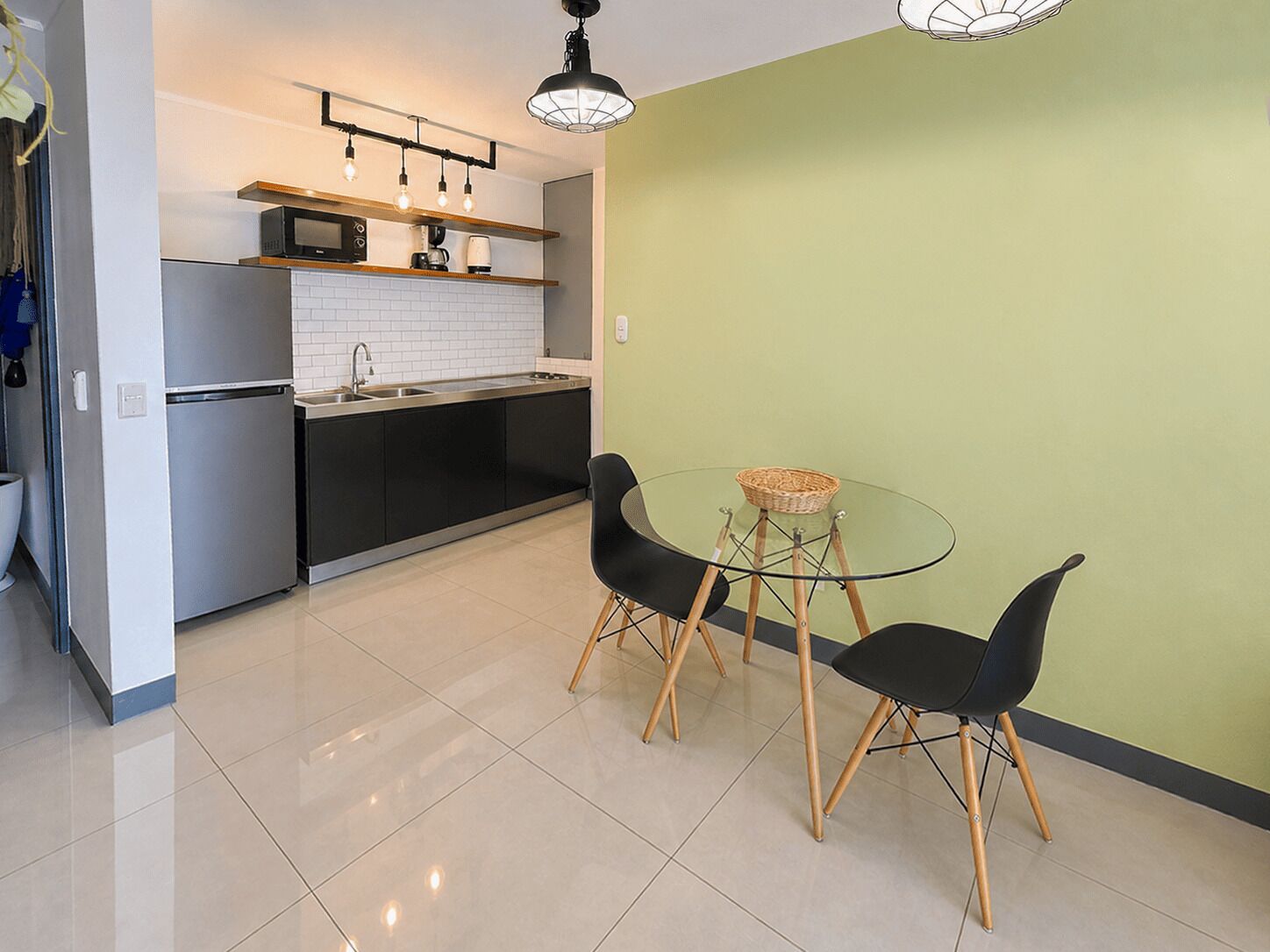 A modern kitchen with a microwave, coffee maker, and a glass table with chairs.