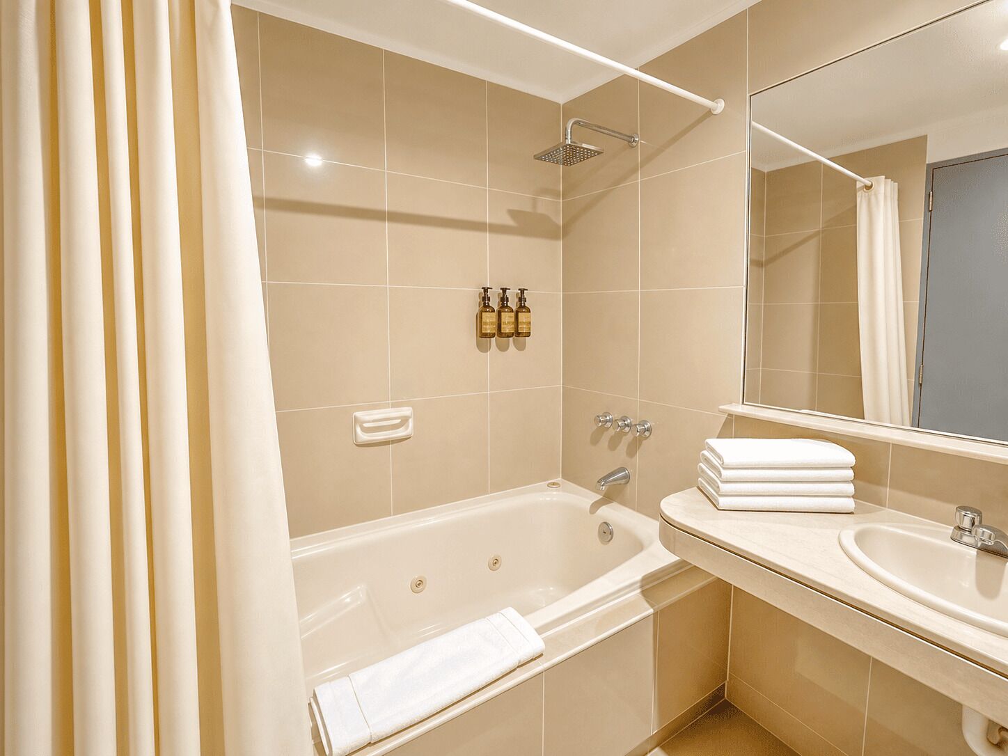 A bathroom with a bathtub, a sink, a mirror, and a showerhead.