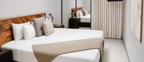 A modern hotel room with a large bed, a flat-screen TV, a bedside table, and a mirror.