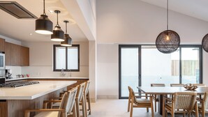 Una cocina moderna con una isla central, sillas de madera e iluminación colgante.