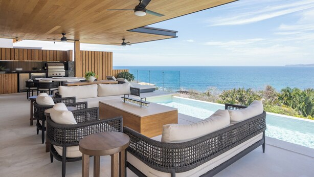 Un área exterior moderna con piscina, mobiliario y vistas al océano.