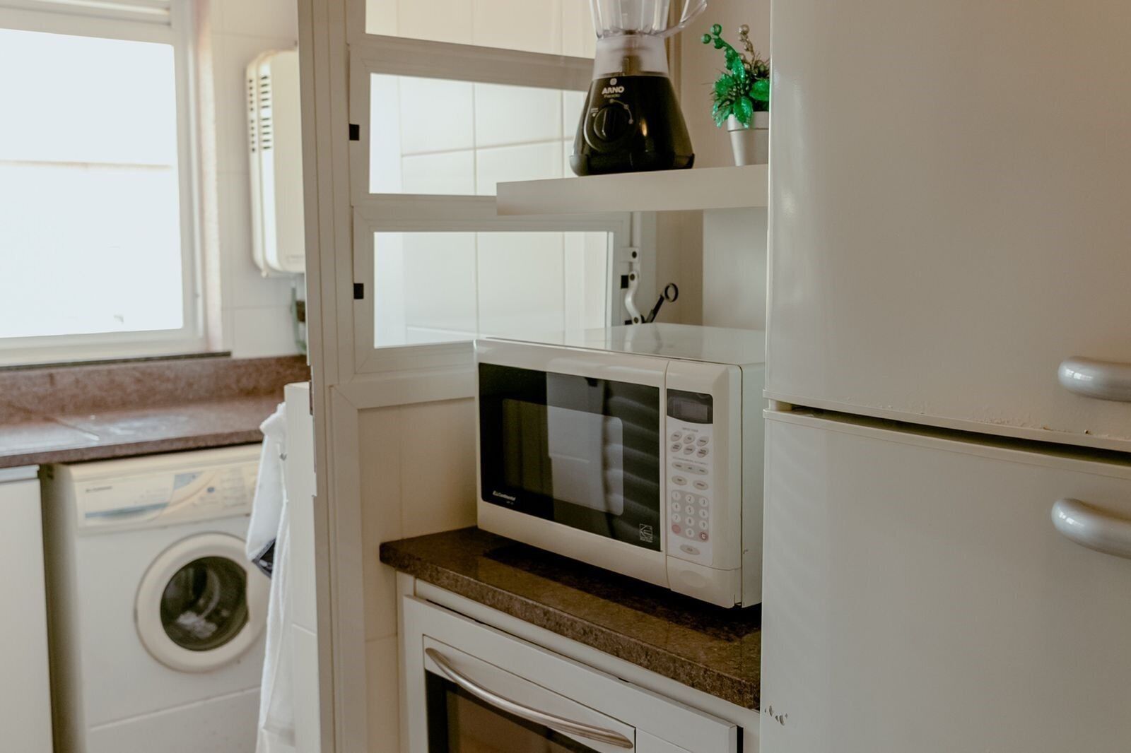 A kitchen with a white microwave, a coffee maker, and a washing machine.