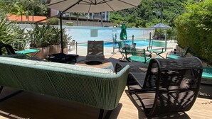 Un espace aménagé au bord de la piscine, avec des chaises longues, une table et un parasol.