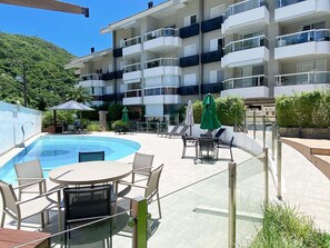 A hotel pool area with a glass-enclosed pool, lounge chairs, and umbrellas.