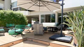 An outdoor patio area with a sofa, chairs, a table, and an umbrella.