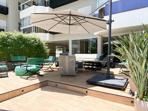 An outdoor patio area with a sofa, chairs, a table, and an umbrella.