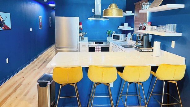 Una cucina moderna con isola centrale, sgabelli da bar e frigorifero in acciaio inossidabile.