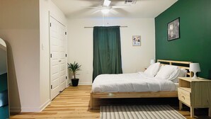 Una camera da letto con un letto, un comodino, una lampada e una ventola a soffitto.