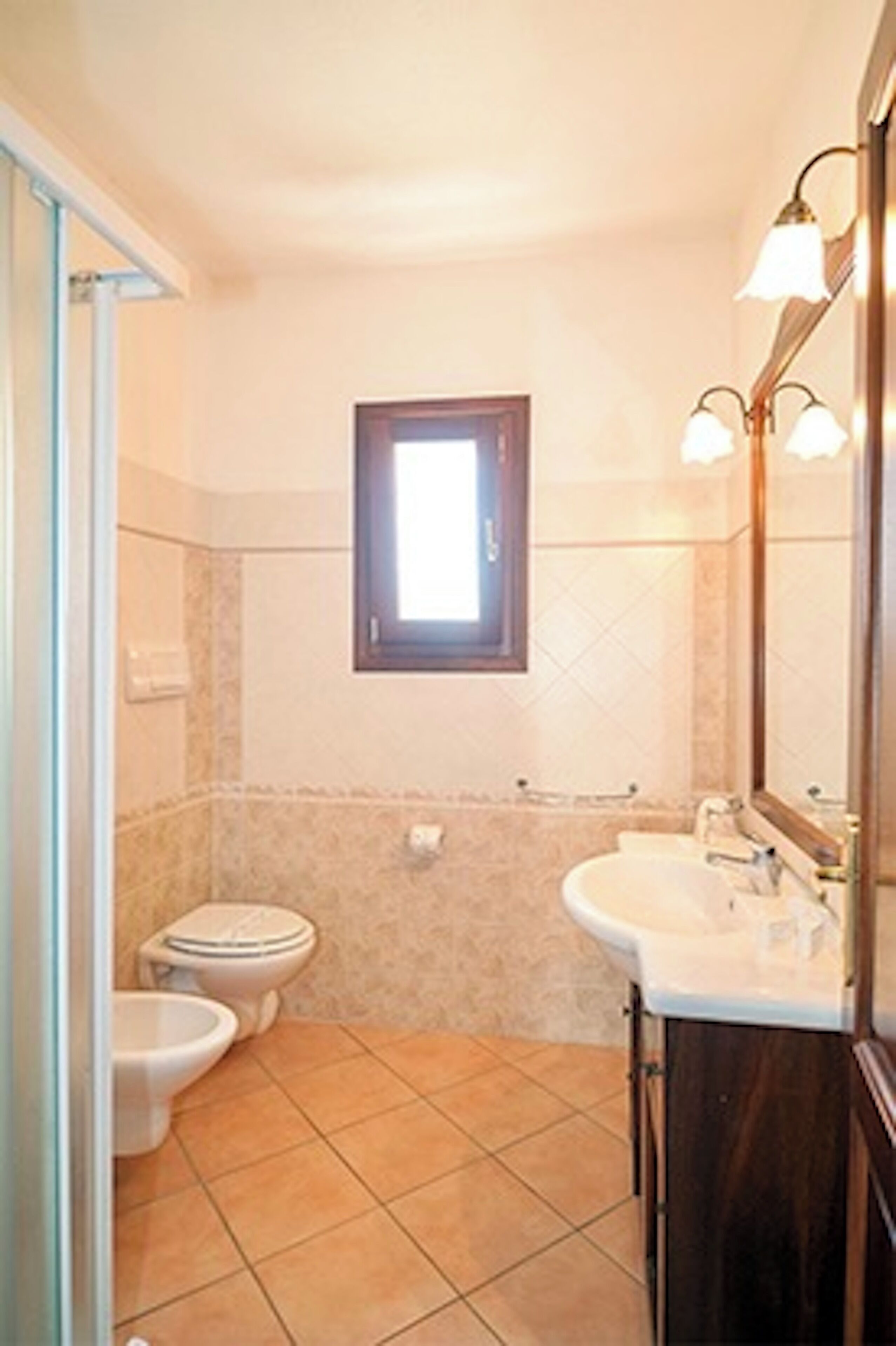 Une salle de bain équipée de toilettes, d’un bidet, d’un lavabo et d’un miroir.