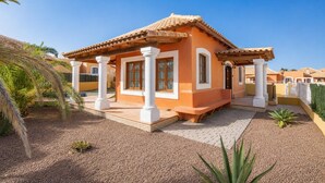A single-story house with a tiled roof, white columns, and a covered patio area.