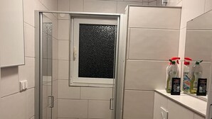A small bathroom with a glass shower enclosure, a toilet, a sink, and a mirror. - NR 5 OG 3 ZKB for families and companies (Fuldatal)